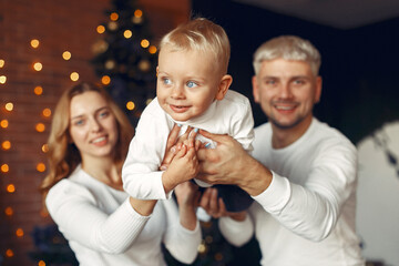 Mother in a white sweater. Family with christmas gifts. Child with parents in a christmas decorations.