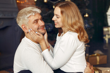 Couple near christmas tree. Lady in a white sweater. Family sitting on a floor.