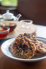Homemade Whole grain Oatmeal Cookie with a background of  tea jug and cup of tea on wooden table