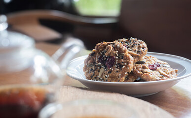 Homemade Whole grain Oatmeal Cookie with a background of  tea jug and cup of tea on wooden table