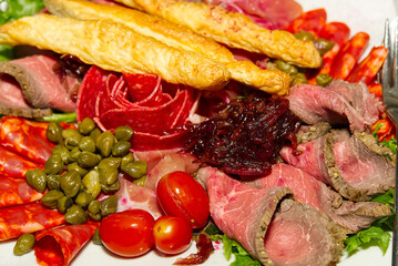 Meat plate antipasti in a restaurant. Party Platter of Assorted Cured Meats, Fruit and Crackers close-up.