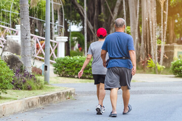 Back view portrait of a Asian elderly man in fitness wear walking and jogging for good health in...