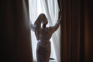 A woman pushes the curtains