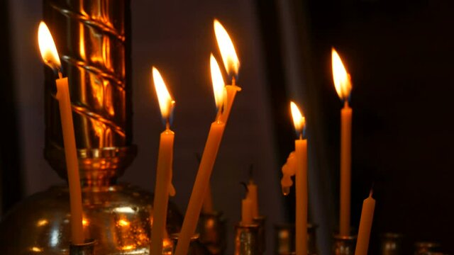 Long thin wax candles burn with a flame in an Orthodox church, memorial rituals for Christians.