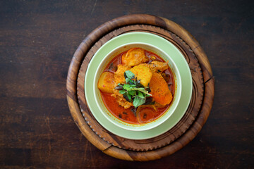 Chicken curry in a green bowl on a wooden base background.