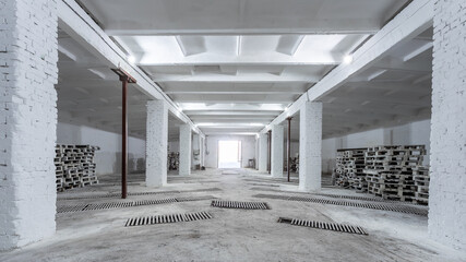 The interior of a huge industrial warehouse made of white bricks with a high ceiling for storing goods. 