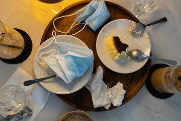 Infectious waste of medical masks,scraps of food and used protective face masks left on plates in...