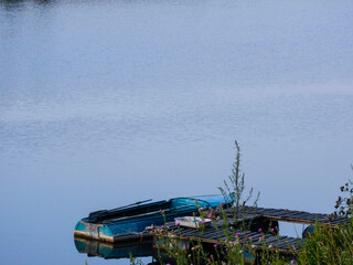 
Metal blue boat with oars on the river at the pier