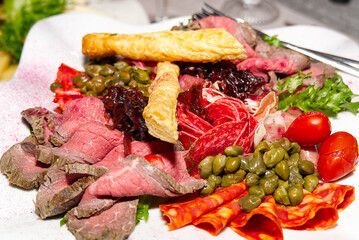 Meat plate antipasti in a restaurant. Party Platter of Assorted Cured Meats, Fruit and Crackers close-up.