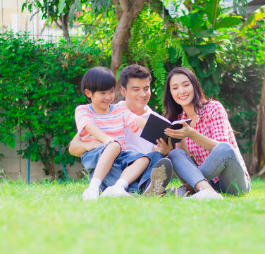 Happy Family Reading Book As Activity Together In Yard At Home