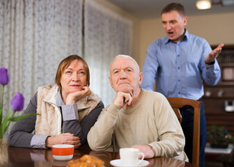 Adult son argues with his elderly parents at home. High quality photo