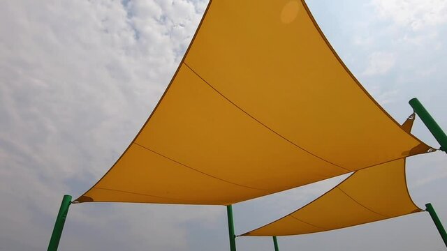 Arc on cloth sun shade sails over playground equipment.