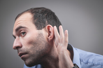 Obraz premium Caucasian man hold hand near ear. Trying to hear a gossip