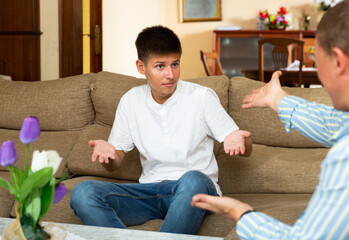 Grumpy father quarrelling with his offended teenage son at home