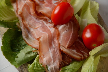 Raw bacon slices on lettuce leaves