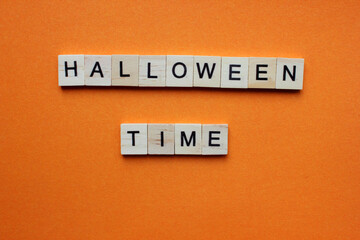 Words Halloween Time. Wooden blocks with an inscription on an orange background. Bulletin board. The concept of the holiday is Halloween. The view from the top. Copy space