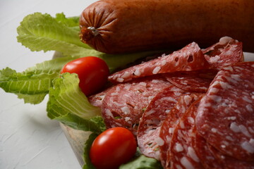 A selection of spicy dried or smoked  sausages on lettuce leaves with cherry tomatoes