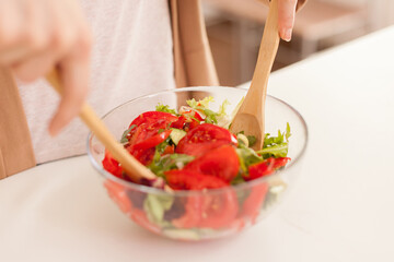 Close up of mixing salad using wooden spoons for breakfast.