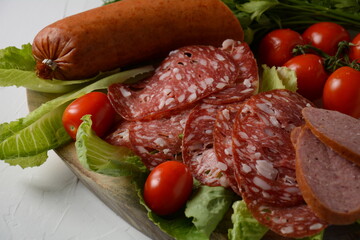 A selection of spicy dried or smoked  sausages on lettuce leaves with cherry tomatoes