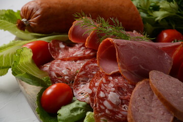 A selection of spicy dried or smoked  sausages on lettuce leaves with cherry tomatoes