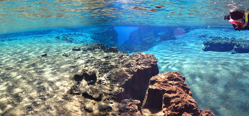 snorkeler in glacial spring water of Silfra, Iceland approaching canyon