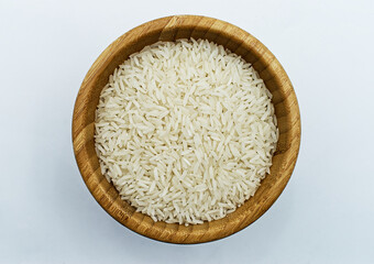 Uncooked Basmati rice in a wooden bowl, isolated on white background. Top view