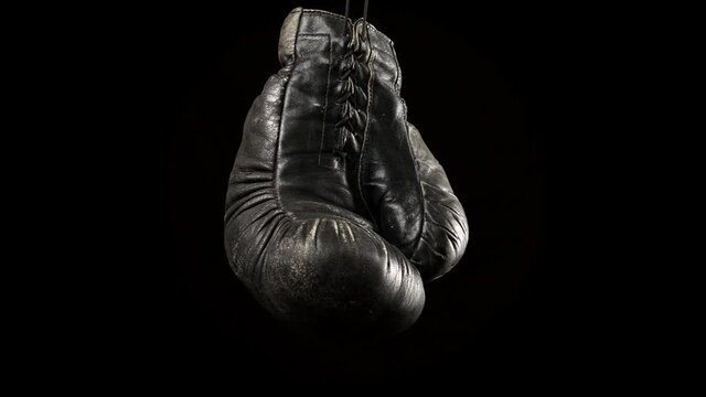 black vintage leather boxing glove hanging on a drawstring, black background