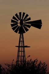 windmill at sunset with tree's north of Hutchinson Kansas USA out in the country.