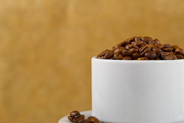 International day of coffee concept. close-up white coffee cup full of coffee beans on beige background.