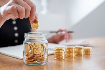 saving money with hand putting coins in jug glass concept financial