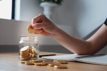 saving money with hand putting coins in jug glass concept financial