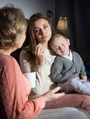 Adult female is crying after watching film and her mother is comforting her in evening at home.