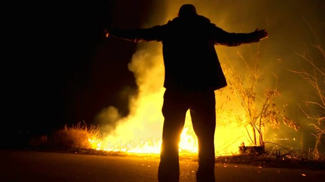 Scary silhouette man with arms outstretched. in a fire at night. halloween. A Man in Front of a Fire