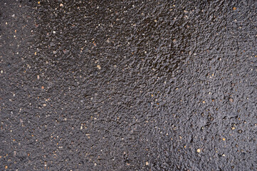 Abstract background of black wet asphalt with inclusions of pebbles