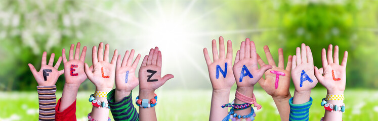 Children Hands Building Colorful Portuguese Word Feliz Natal Means Merry Christmas. Sunny Green Grass Meadow As Background