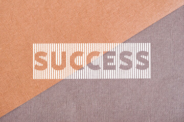 On a textured brown background divided by a diagonal, the inscription is made through a stencil....