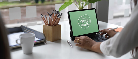 Female office worker working on her project with mock up tablet in office room
