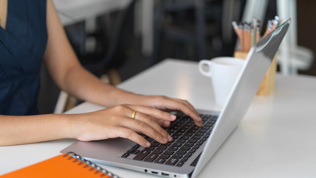 Female typing on laptop computer while working on her project in office room