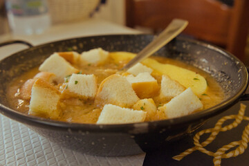 Delicious Italian fish soup with sardines, prawns, shells and bread croutons