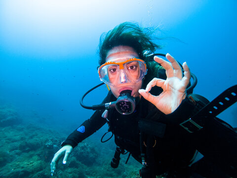 A young female diver making OK sign underwater looking at the camera. Underwater concept