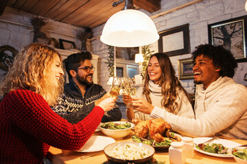 Group of friends eating dinner together, cheering with champagne 