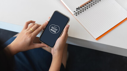 Businesswoman holding mock up smartphone in office room