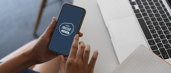 Female touching mock up smartphone while working oh the project