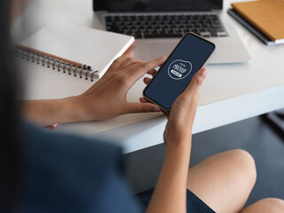 Young female adult using mock up smartphone while sitting in office room