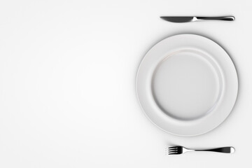 White ceramic plate with knife and fork on the sides. View from above. Copy space.