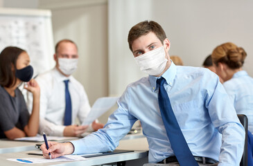 business, people and pandemic concept - businessman wearing face protective medical mask for protection from virus disease at office