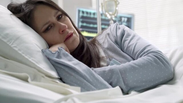 sad pensive mature female patient on hospital bed,distressed woman feeling depressed and alone
