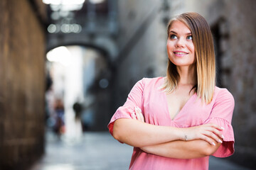 Young romantic woman looking around and walking on old town street