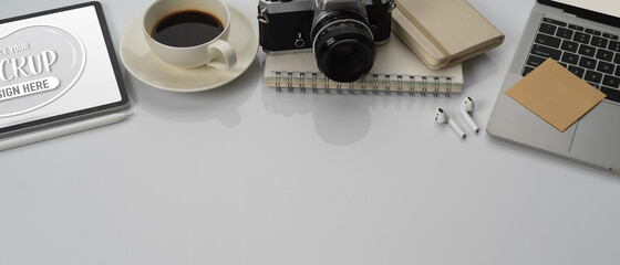 Worktable with copy space, laptop, mock up tablet, notebooks, camera, coffee cup and accessories