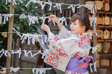 おみくじを結ぶ浴衣姿の女性
